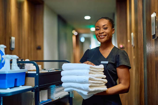 The supplied Cleanqueens team photo, showing a cleaner with fresh towels and cleaning supplies